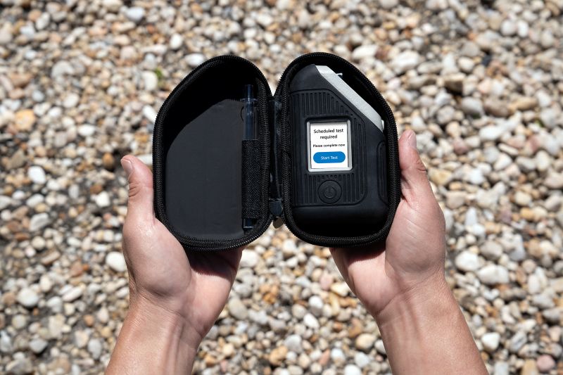 Hands holding the discreet carrying case for portable alcohol breathalyzer BI SoberTech.