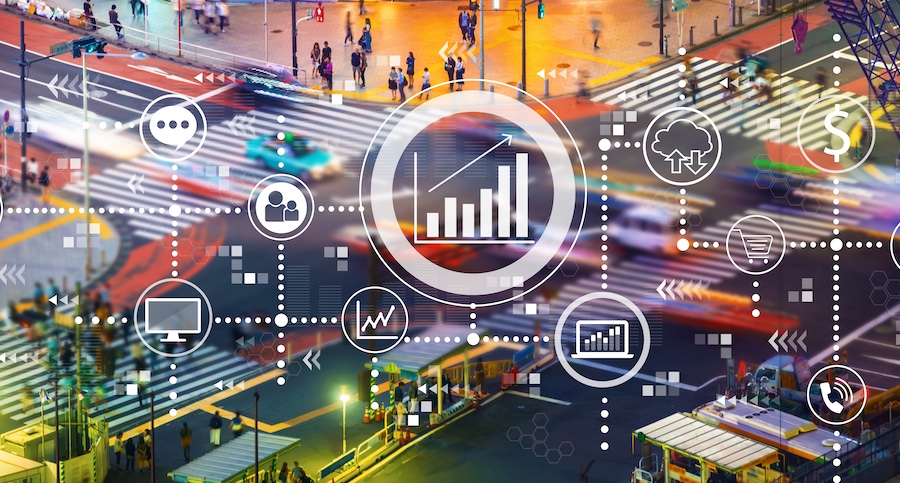 Digital visualization of a modern street intersection overlaid with technology interface icons demonstrating location tracking data exchange points, including GPS, cellular, and RF signal indicators
